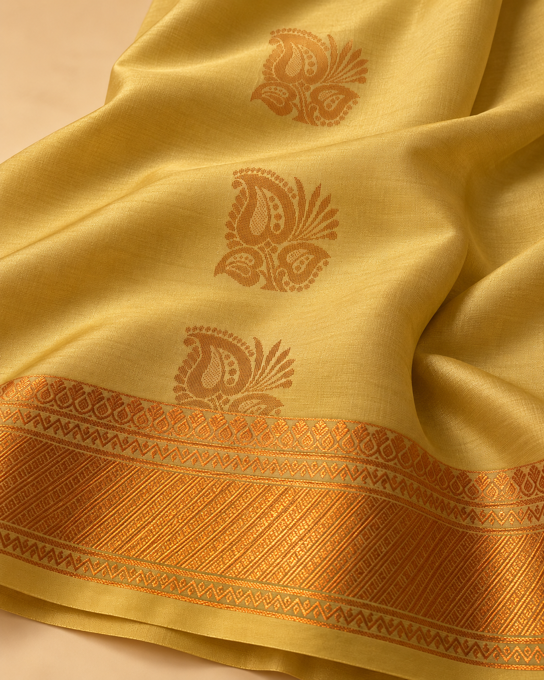 Copper paisley and geometric border detail — muted gold silk saree