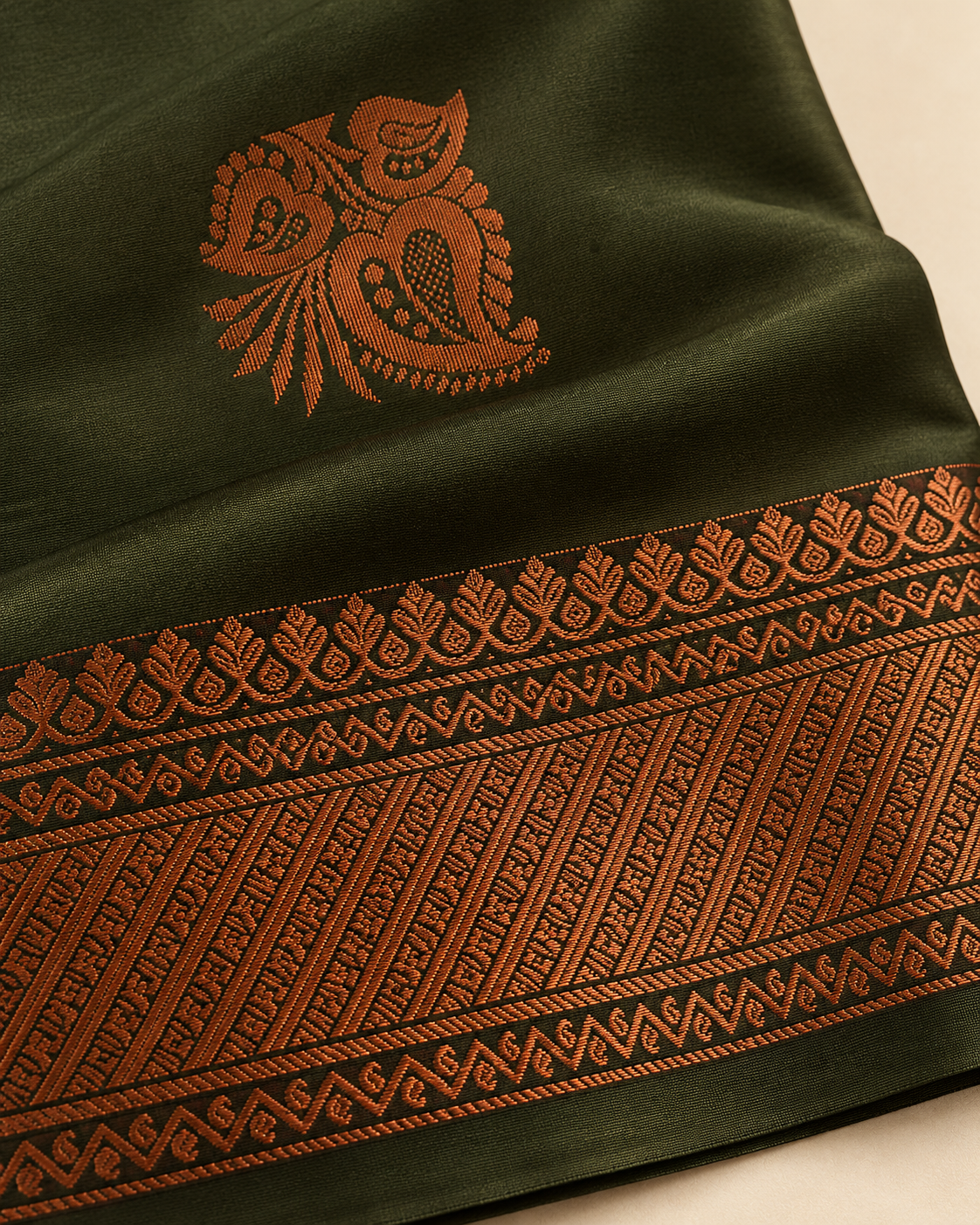 Close-up of a copper paisley cluster motif and geometric border on olive green silk