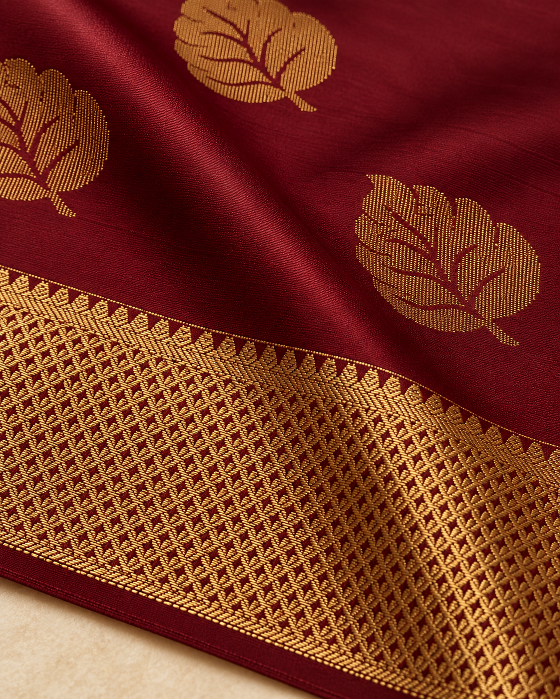 Close-up of a gold leaf motif and geometric gold border on wine maroon silk