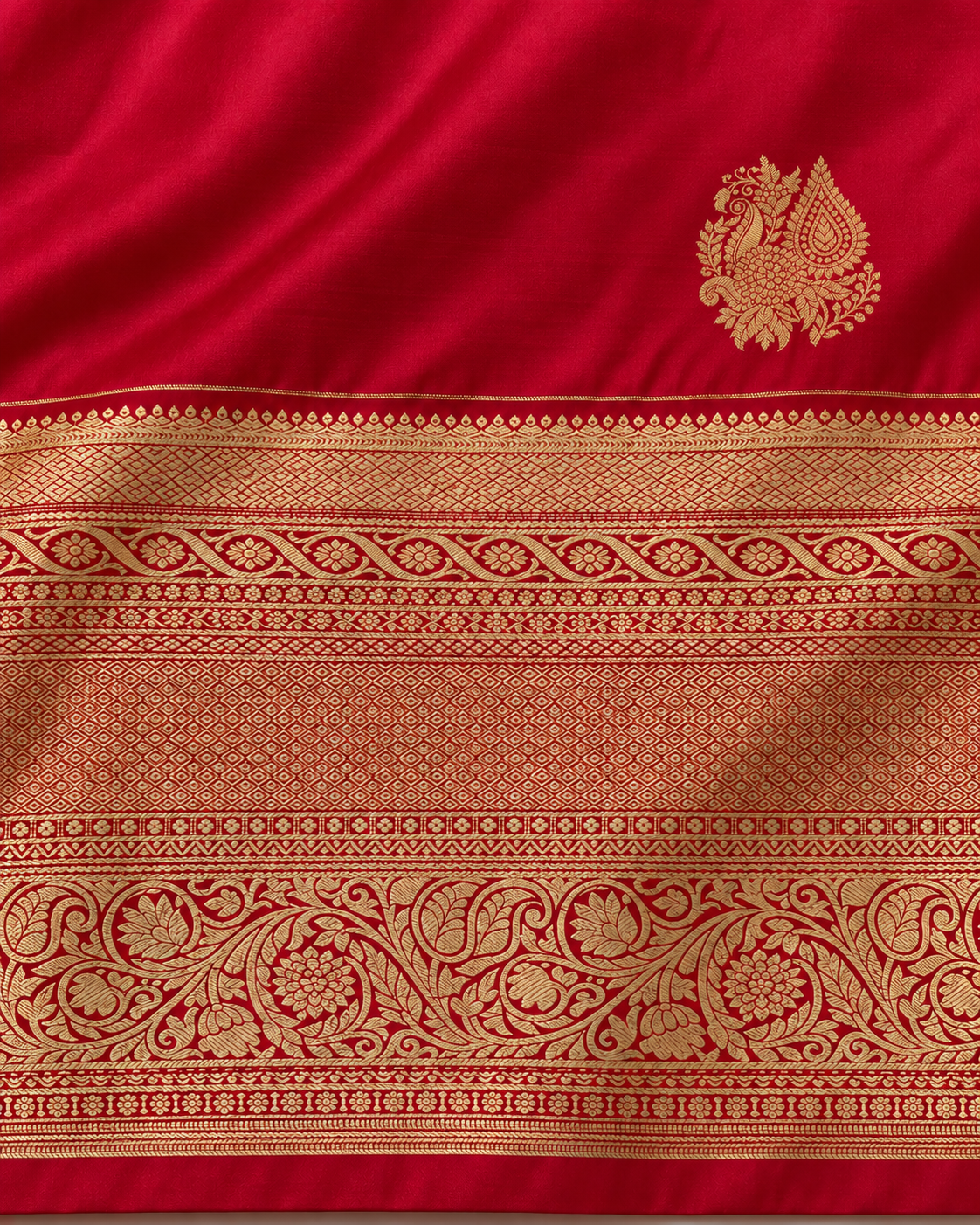 Close-up of small gold peacock paisley motif and ornate border on ruby red silk