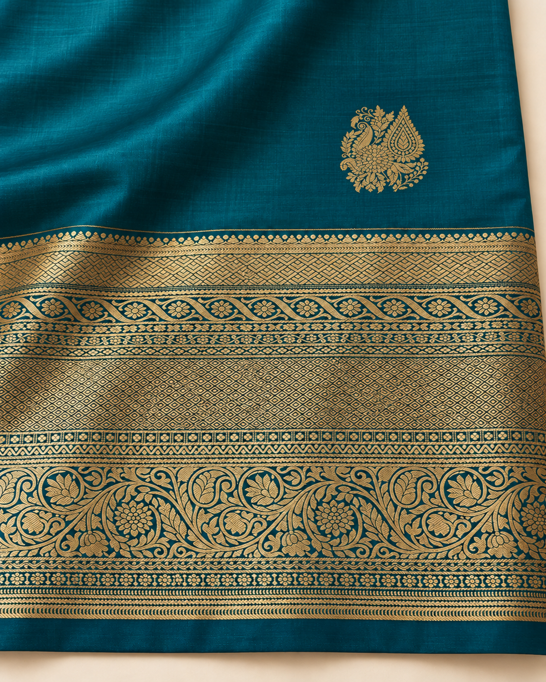 Close-up of small gold peacock paisley motif and ornate border on teal blue silk saree