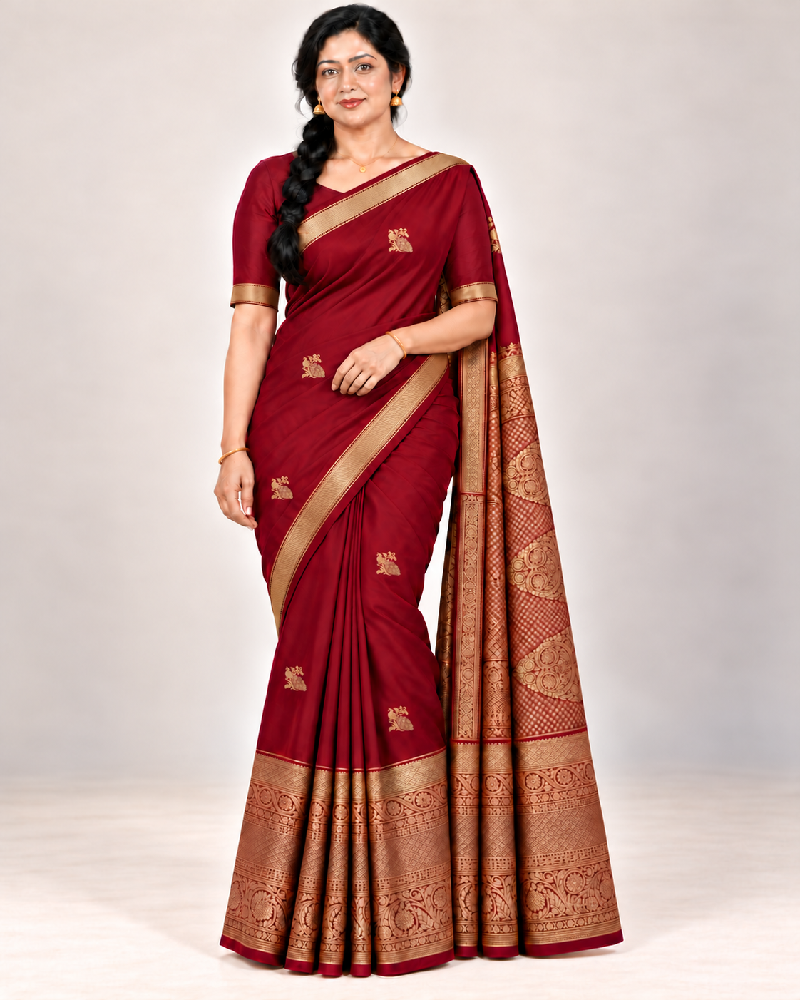 Wine red silk saree in a relaxed front pose with matching blouse and gold jewellery